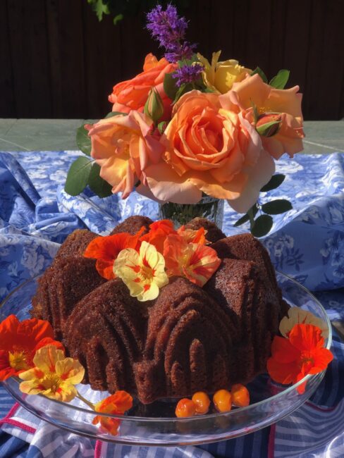 citrus olive oil bundt cake on a platter decorated with flowers