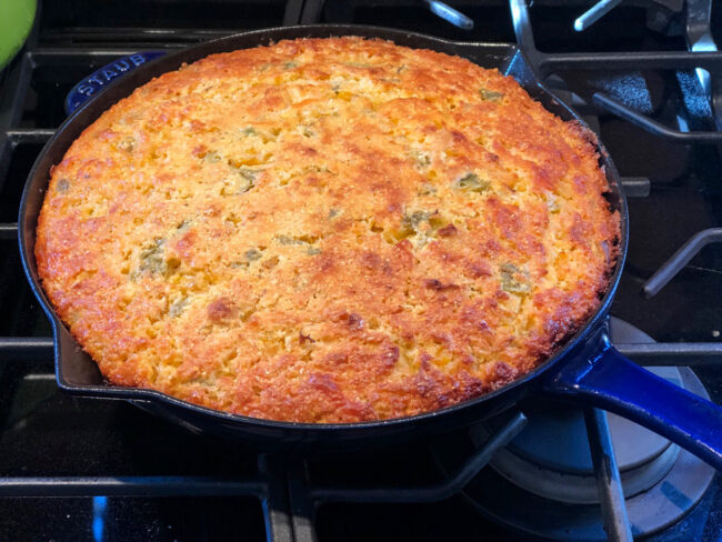 Skillet Hatch Chile Cornbread with Hatch Chile Honey Butter on the skillet cooling