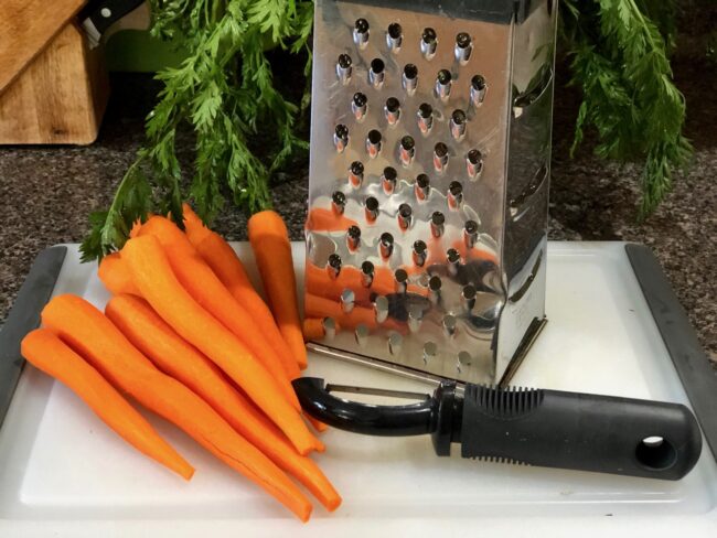 peeled carrots next to a grater