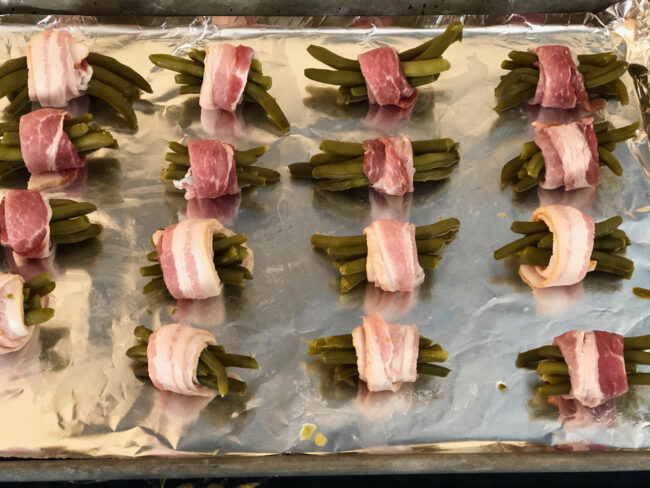 green bean bacon bundles spread over baking tray
